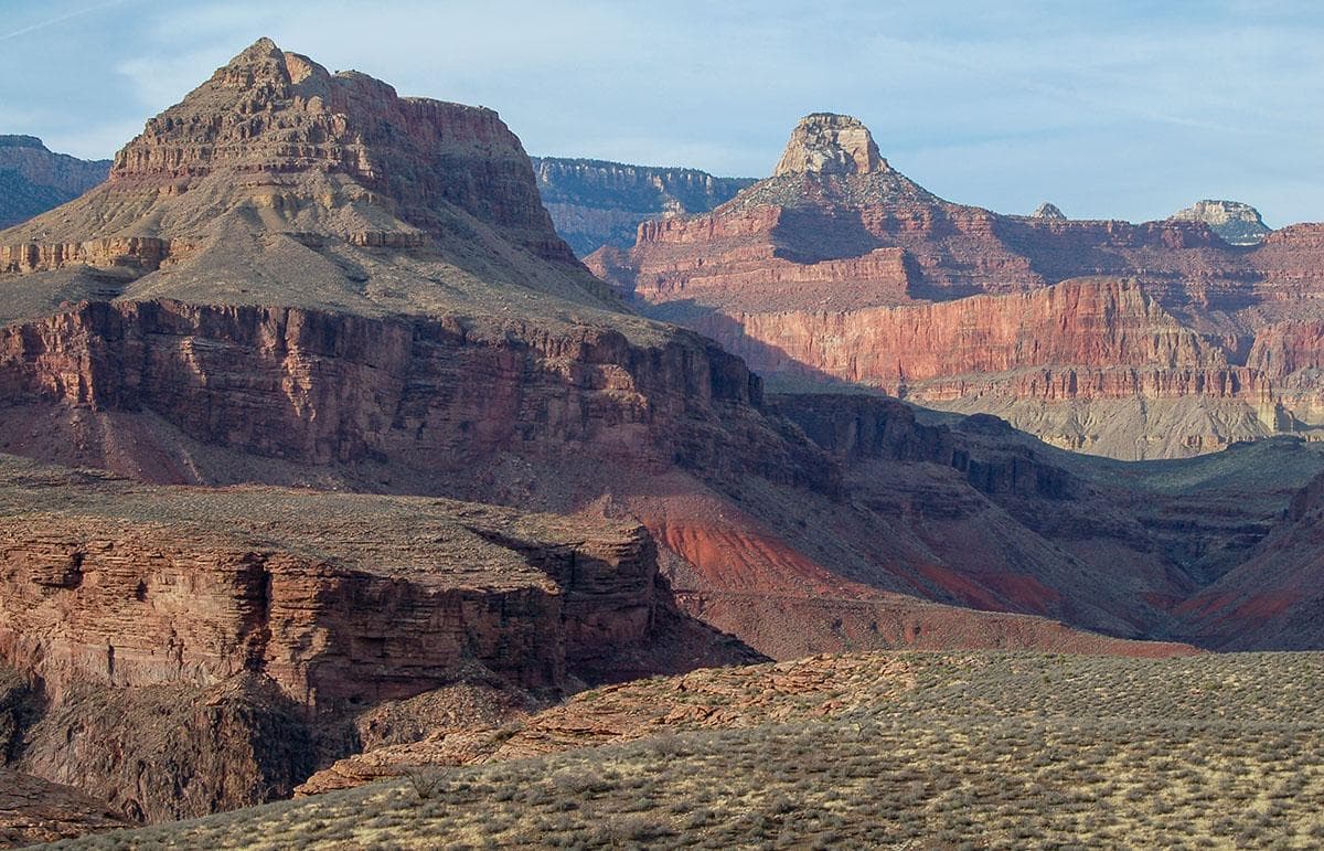 a series of colorful and foreshortened plateaus, cliffs and slopes create two peaks that tower above