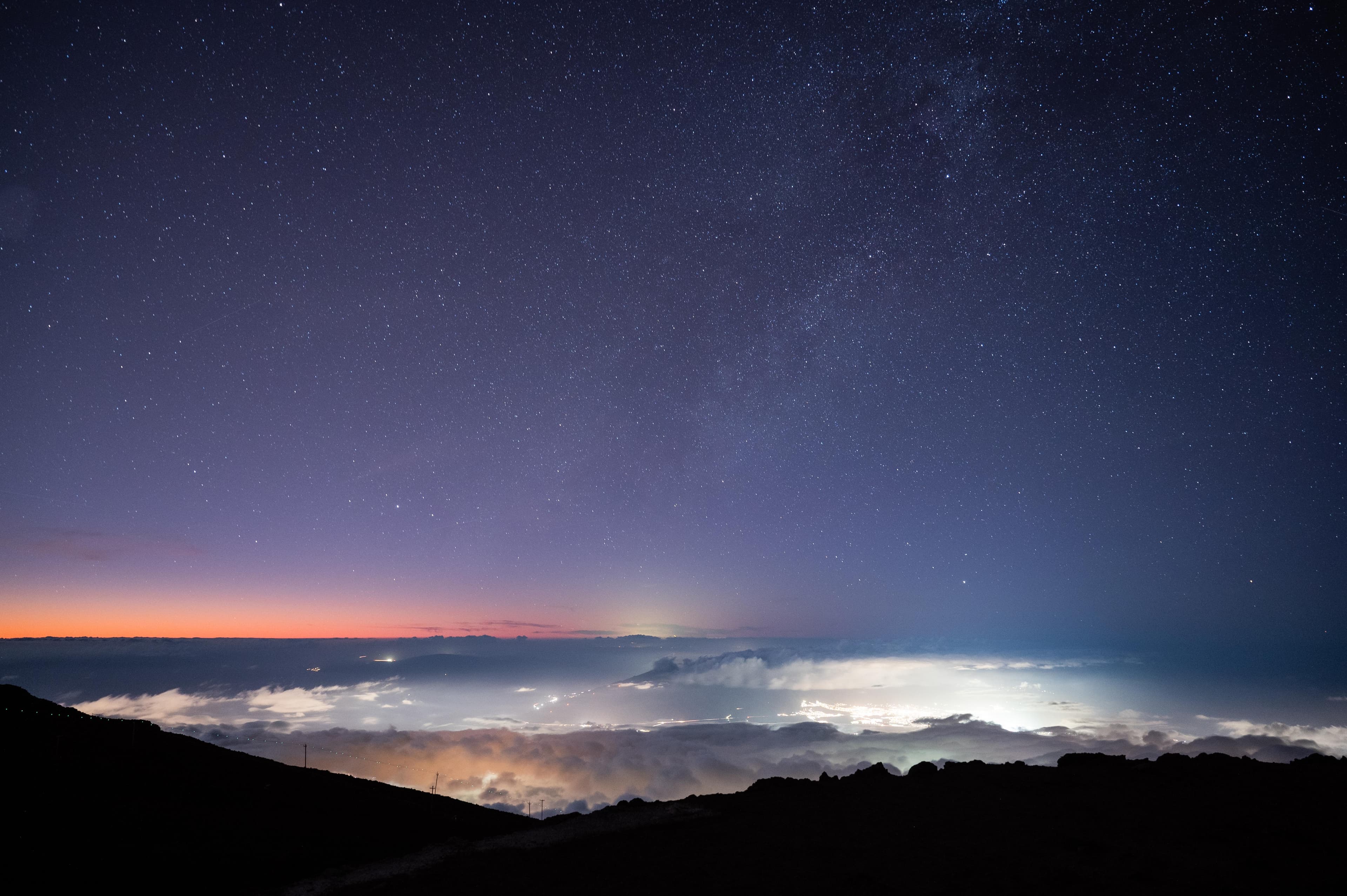 A purple star-filled sky over illuminated clouds